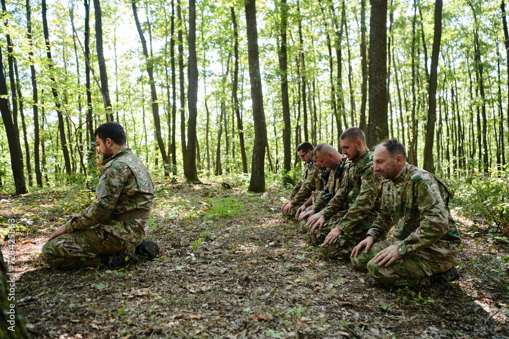 A dedicated group of soldiers engages in Islamic prayer amidst the challenging and perilous conditions of a military operation in dense forested areas