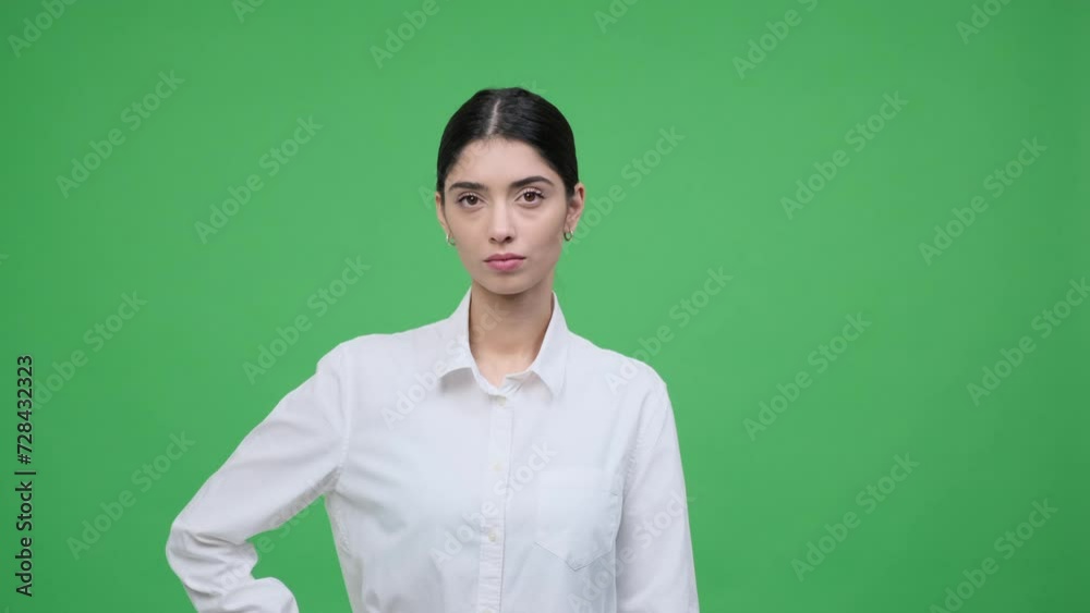 Portrait of a serious, stern Caucasian woman in formal wear standing over green background and looking at camera. Focused female businessperson. Portrait of a serious, stern Caucasian woman in formal wear standing over green background and looking at camera. Focused female businessperson.