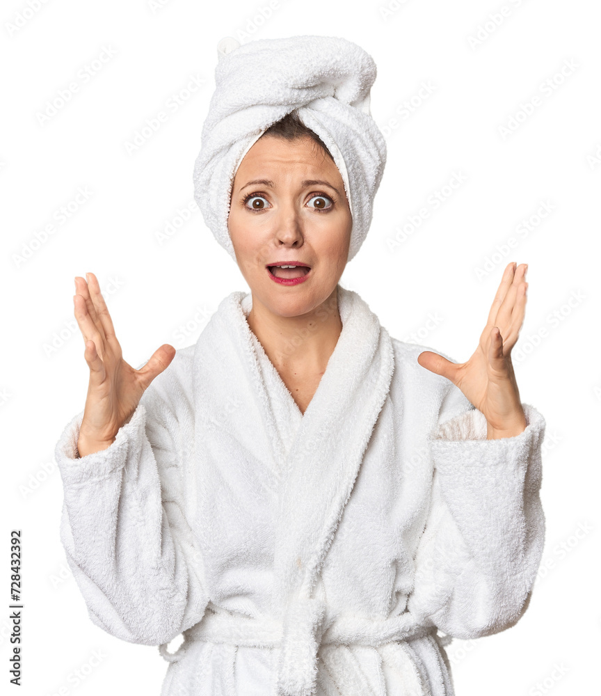 Caucasian woman in bathrobe and towel screaming to the sky, looking up, frustrated.