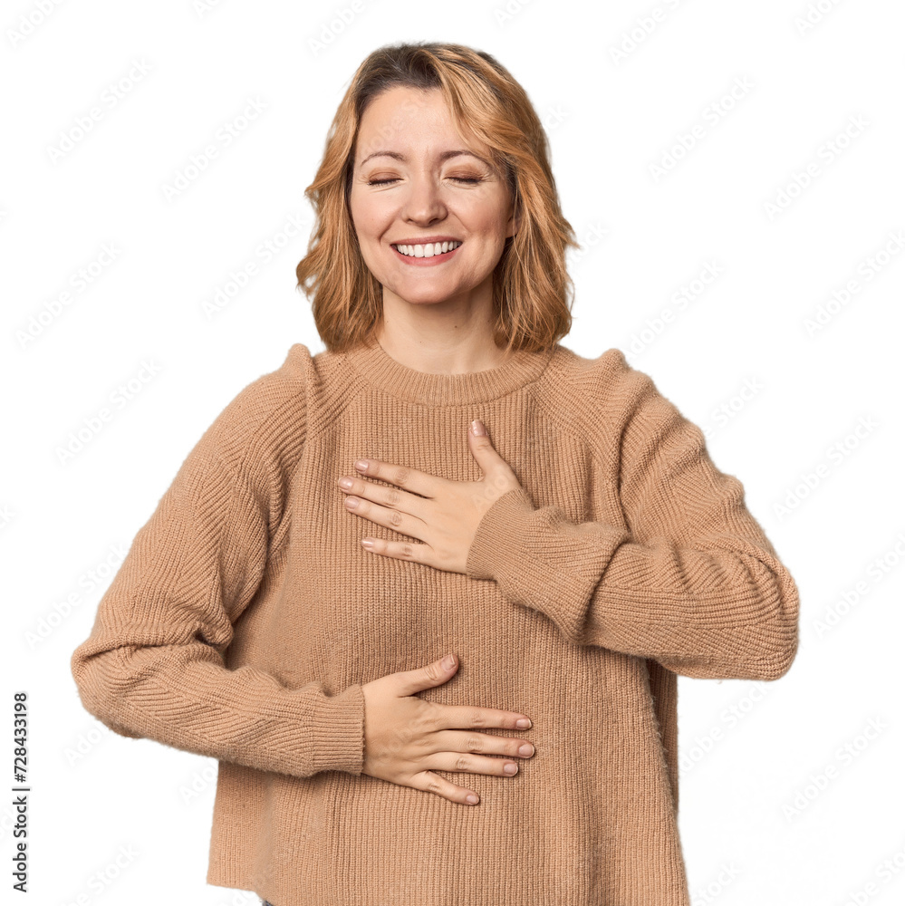 Blonde middle-aged Caucasian woman in studio laughs happily and has fun keeping hands on stomach. Blonde middle-aged Caucasian woman in studio laughs happily and has fun keeping hands on stomach.