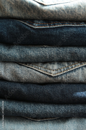  Close up the Stack of jeans in different shades of blue. Folded denim jeans pants, different shades of denim jeans in a row. Denim texture or denim jeans background.