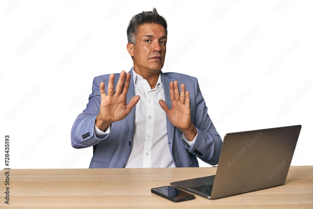 Elegant businessman at desk with laptop being shocked due to an imminent danger Elegant businessman at desk with laptop being shocked due to an imminent danger