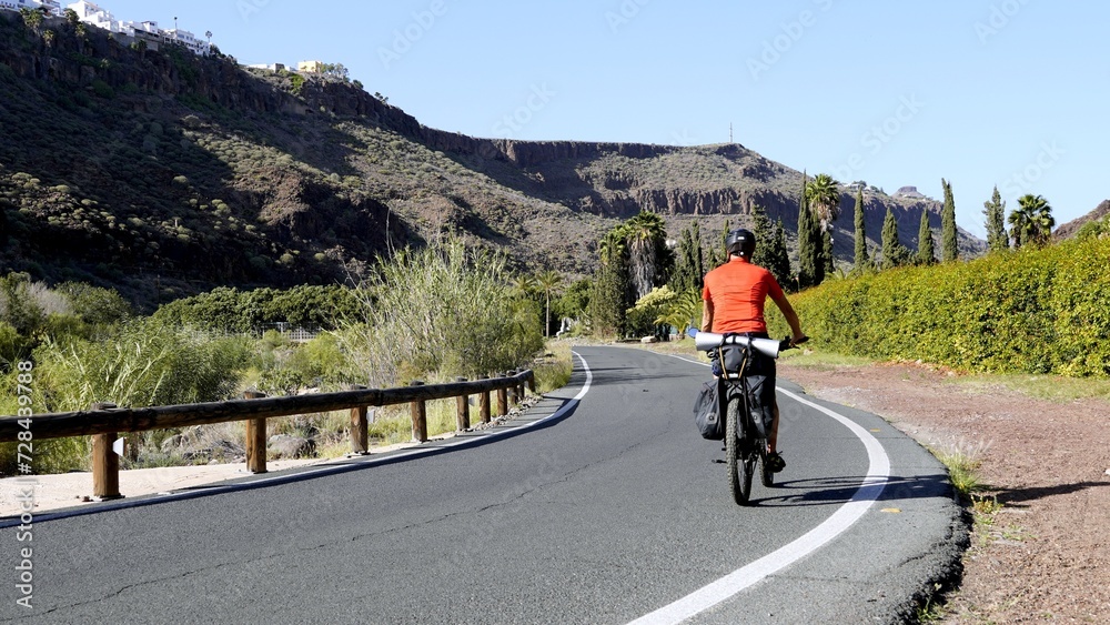 Cyclist with bicycle equipped with luggage travels on the mountain road of Gran Canaria in the Canary Islands