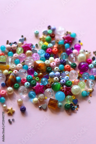 Various colorful beads on bright pink background. Selective focus.