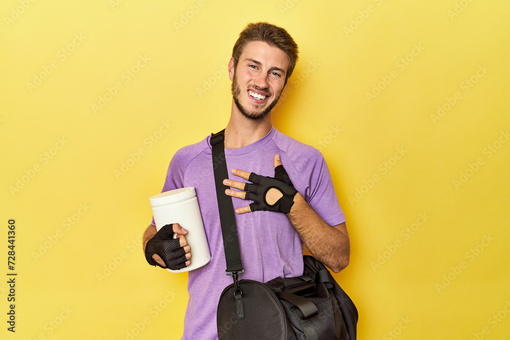 Man with protein jar and backpack on yellow laughs out loudly keeping hand on chest. Man with protein jar and backpack on yellow laughs out loudly keeping hand on chest.