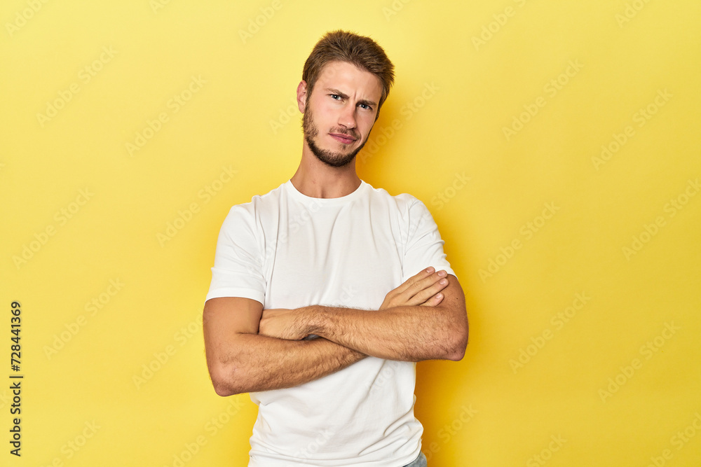 Young Caucasian man on a yellow studio background suspicious, uncertain, examining you. Young Caucasian man on a yellow studio background suspicious, uncertain, examining you.