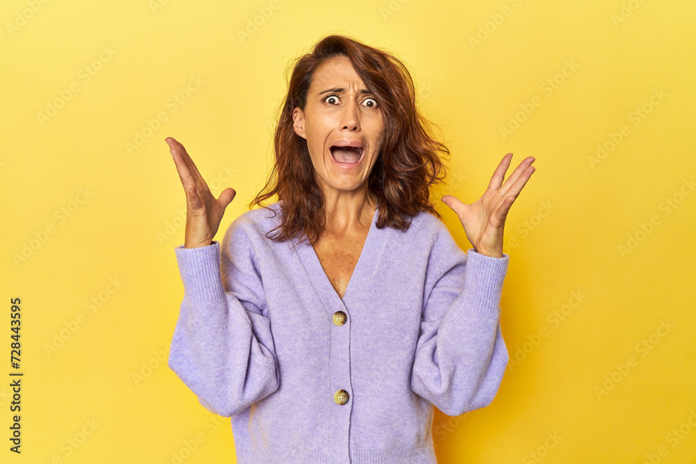 Middle-aged woman on a yellow backdrop screaming to the sky, looking up, frustrated. Middle-aged woman on a yellow backdrop screaming to the sky, looking up, frustrated.