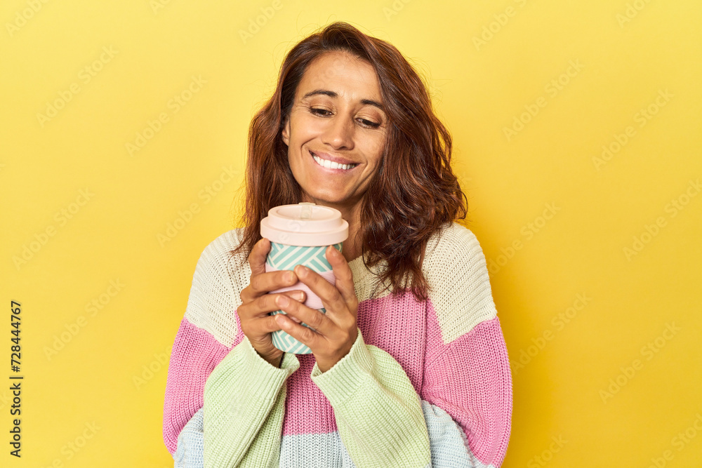 Middle-aged woman with takeaway coffee on yellow Middle-aged woman with takeaway coffee on yellow