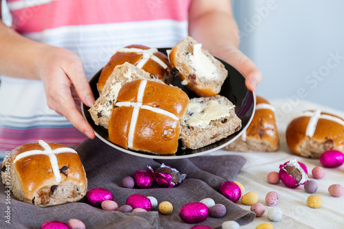 Buttered hot cross buns and scattered eggs at Easter on a plate photo