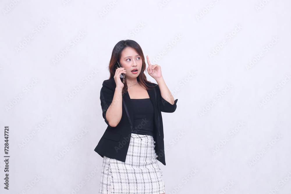 the charm of a beautiful Asian office woman in her 20s with a surprised expression while making a phone call on a cellphone gadget while pointing her hand up isolated on a white background the charm of a beautiful Asian office woman in her 20s with a surprised expression while making a phone call on a cellphone gadget while pointing her hand up isolated on a white background