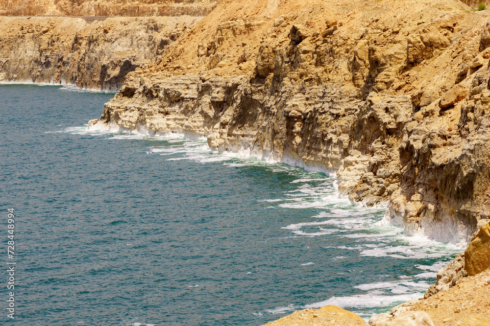 Obraz premium Shore of Dead Sea of Jordan side. Emerald water of Dead Sea leaves, exposing stepped sandy coast. Traces of dying sea. Spring 2011. Ecology theme.