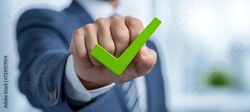 Businessman holding hologram of green compliance tick for certification or audit concept photo