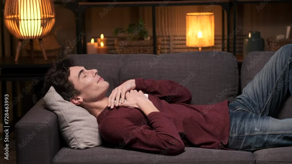 Happy man is texting on the phone with girlfriend, embracing phone, rejoicing late at night on the sofa in the living room. Online dating, lovers connection. Happy man is texting on the phone with girlfriend, embracing phone, rejoicing late at night on the sofa in the living room. Online dating, lovers connection.