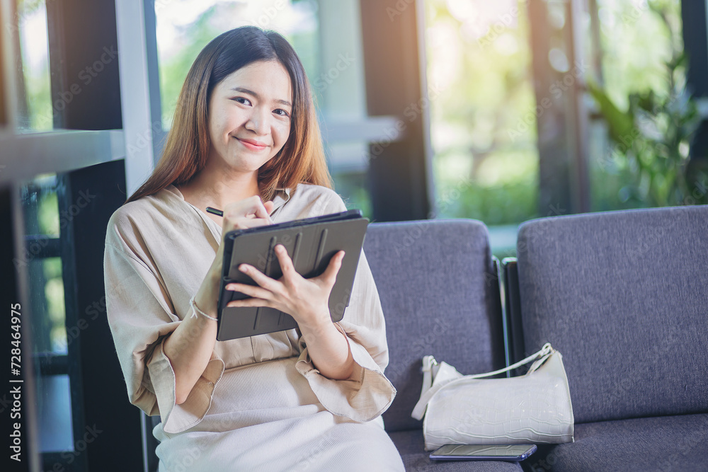 Attractive businesswoman using digital tablet computer at workplace. Businesswoman hand holding pen and touching screen of tablet device.