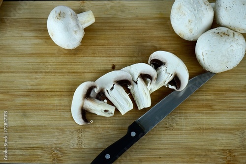 whole and folk champignons on a wooden board and a knife lies nearby