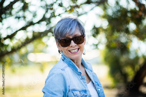 portrait of a senior woman in the garden wearing sunglasses photo