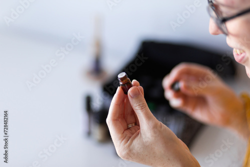 Young woman smelling bottle of essential oils photo
