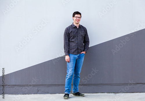 Person standing beside wall in urban area - full length body shot of young man photo
