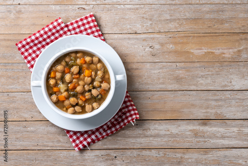 Chickpeas soup with vegetables in bowl on wooden table. Top view. Copy space