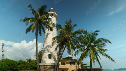Galle Lighthouse at Galle Fort, Sri Lanka. Action. Beautiful palm trees and blue cloudy sky.