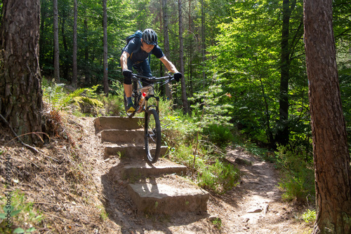 Mountainbiker im Pfälzerwald fährt einen schwierigen Singletrail mit mehreren Stufen (model released)