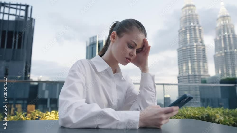 Business woman with phone in hand seriously looking into the phone screen and angry at the background of the city and skyscrapers in the afternoon, lifestyle modern urban freelancer Business woman with phone in hand seriously looking into the phone screen and angry at the background of the city and skyscrapers in the afternoon, lifestyle modern urban freelancer