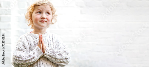 serene expression as the child clasps their hands in quiet prayer. photo