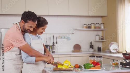 Romantic young couples cooking together by chopping vegetables at kitchen - concept of intimacy, relationship affection and companionship