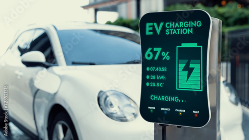 Futuristic clean energy utilization of smart EV charging station in residential area recharging electric car's battery. Technological advancement of high-tech EV car in modern city lifestyle. Peruse