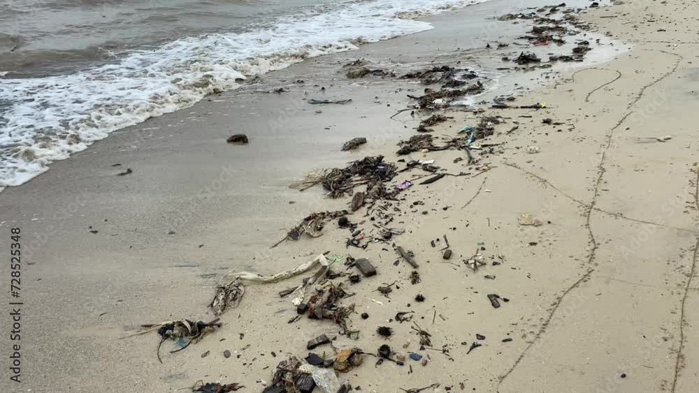 Grey sand beach with waste and muddy sea water Grey sand beach with waste and muddy sea water
