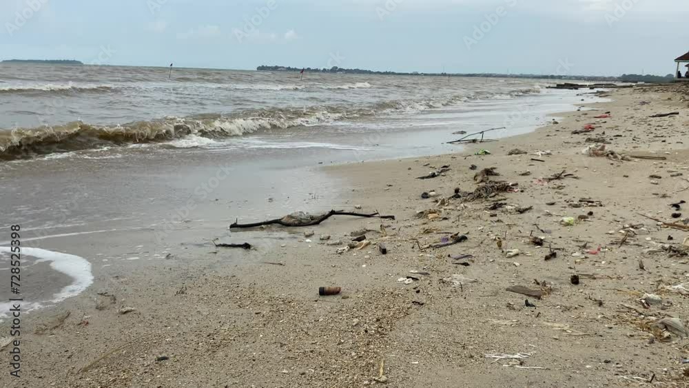 Grey sand beach with waste and muddy sea water Grey sand beach with waste and muddy sea water