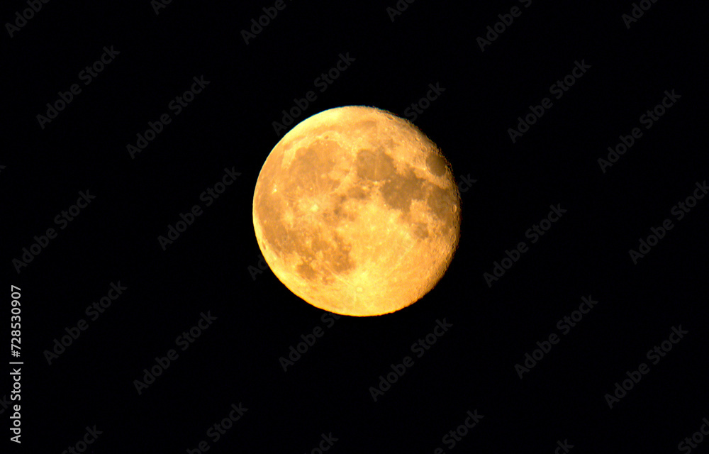 Obraz premium Yellow orange supermoon with its lunar craters on the surface