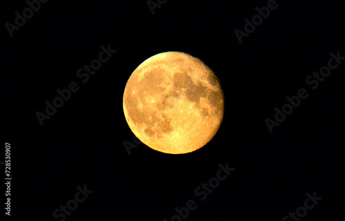 Yellow orange supermoon with its lunar craters on the surface