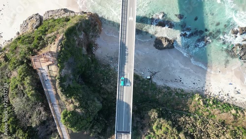 Panoramic drone aerial view of a large bridge and blue cars over a beautiful blue ocean with waves, at Tsunoshima Ohashi Bridge, Yamagata Prefecture, Japan, photo