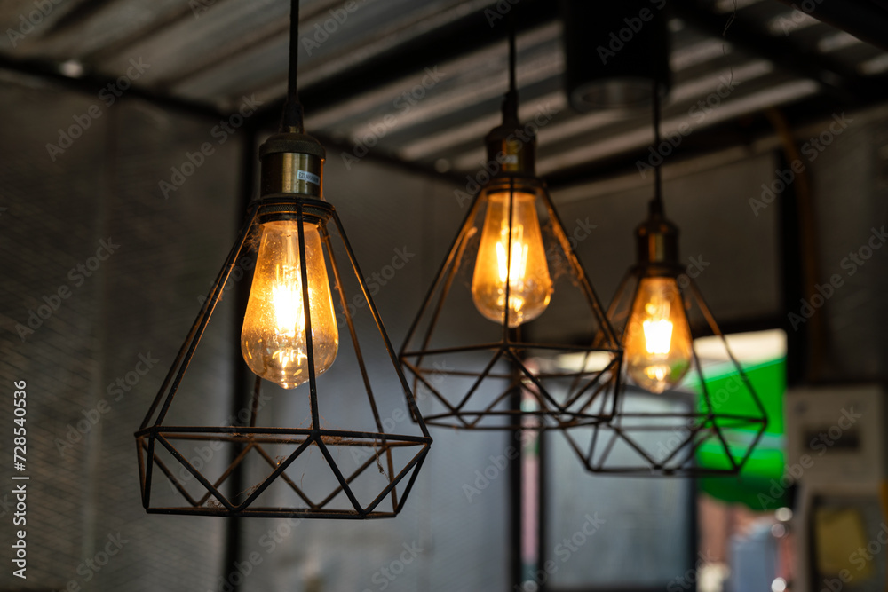 Classic style lightbulb ceiling lamp with iron cage glowing in orange light shade. Interior decoration object photo, selective focus. Classic style lightbulb ceiling lamp with iron cage glowing in orange light shade. Interior decoration object photo, selective focus.