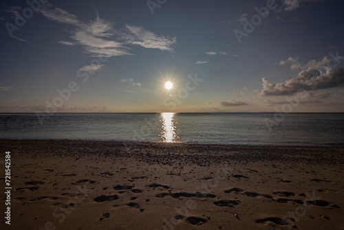 Sunset, footprints in the sand, heavenly view and calm sea reflections on Okinawa beach in Japan. Japanese island vacation for a coastal calmness and adventure, horizontal image
