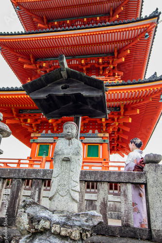 Sublime and famous orange ancient Japanese temple in Kyoto, Japan with unrecognizable Geisha at the foot of the temple, vertical image