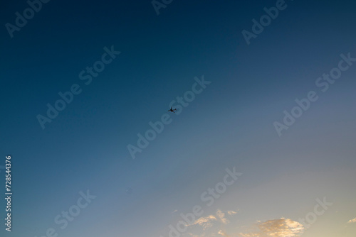 Distant view of a plane in the blue and orange sky of Okinawa, Japan, during a sunset, nobody, horizontal image