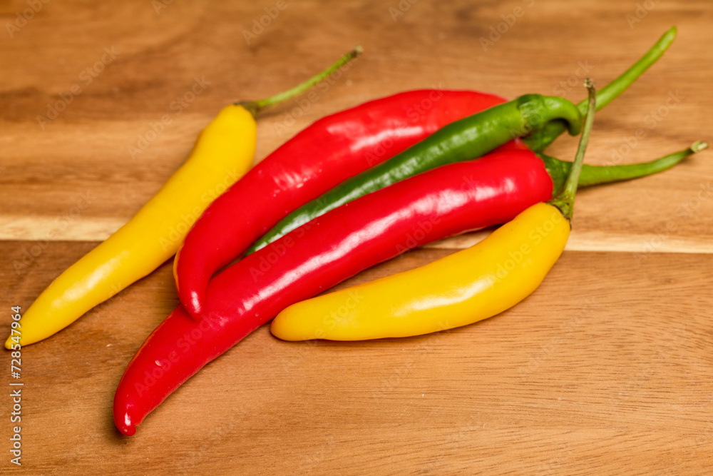 Hot peppers of different colors on a wooden chopper