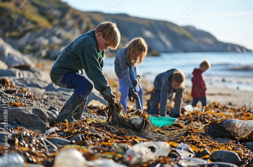 Children engage in a beach cleanup, diligently picking up trash amidst seaweed and rocks, contributing to environmental conservation efforts photo