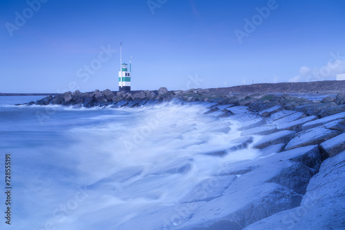 A lighthouse on the beach during blue hour. A landmark in maritime navigation. Long exposure. Natural composition. Photo for wallpaper and background.