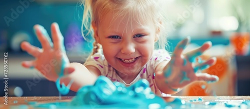 Blonde child playing with slime on desk  promoting sensory development.