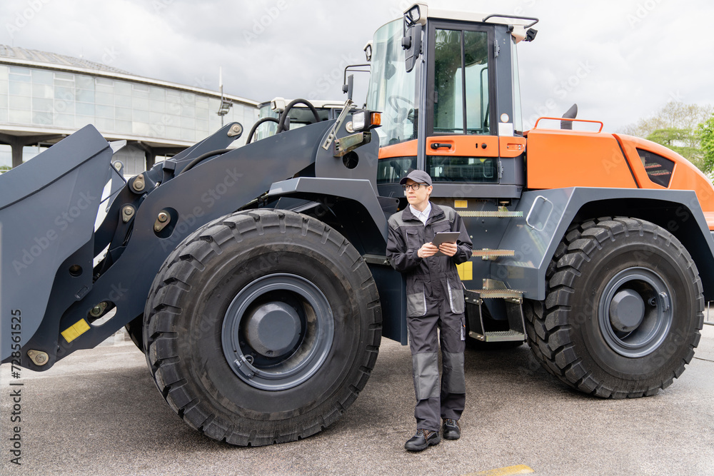 Serviceman with digital tablet on a background of the tractor. Serviceman with digital tablet on a background of the tractor.