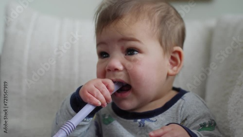 closeup shot of a baby boy chewing on a teething straw photo