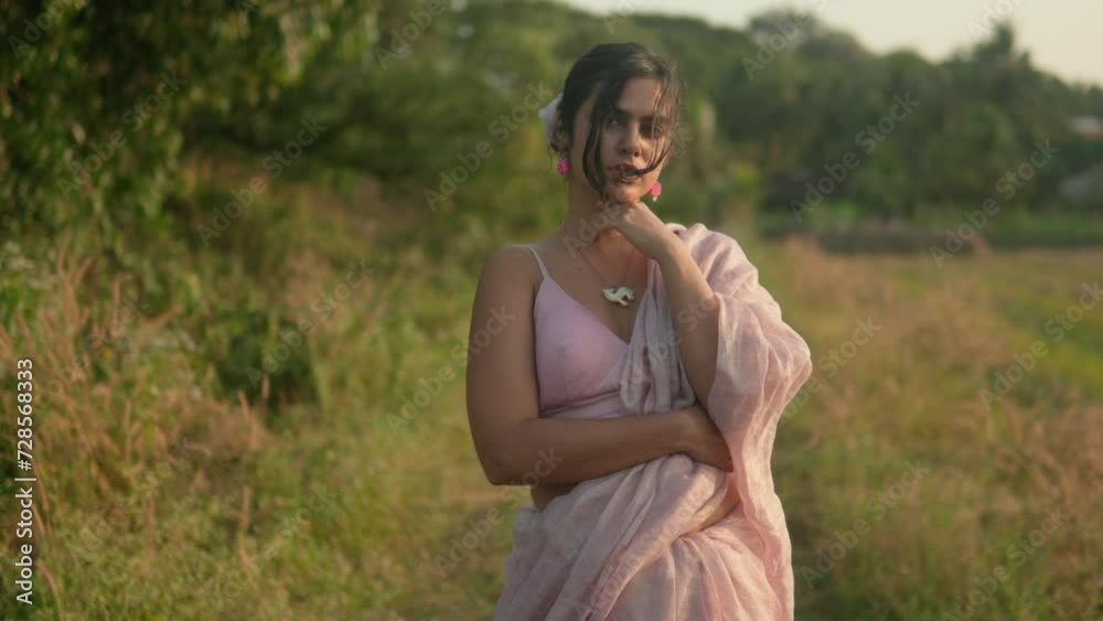 Elegant woman in pink dress posing thoughtfully in rural setting, golden hour Elegant woman in pink dress posing thoughtfully in rural setting, golden hour