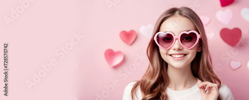 Happy smiling girl in heart shaped glasses on pink pastel background. St Valentines Day, International Women's Day, Love concept.Banner for design with space for text.Generative AI