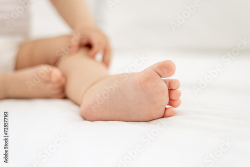 Stampa su tela close-up of legs and arms of a small child a girl or a boy in a white bodice on