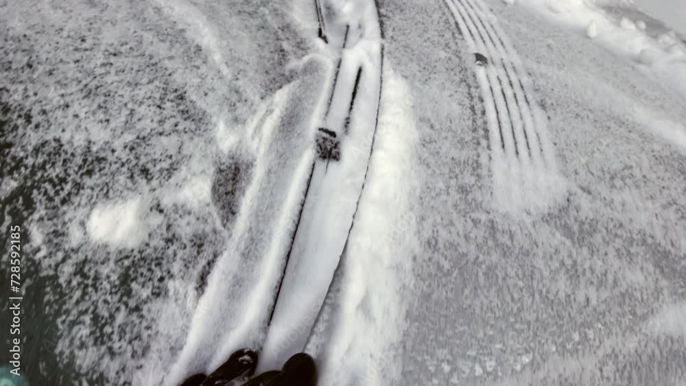 Man with brown leather gloves uncovering the car front window from frozen snow in winter
