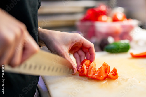 Chef hand cut tomatoes on a chopping board