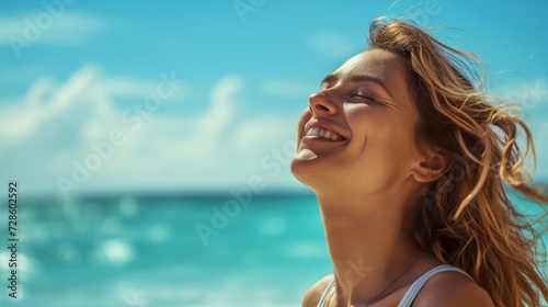 A woman can be seen laughing joyfully on the beach as the waves crash behind her.